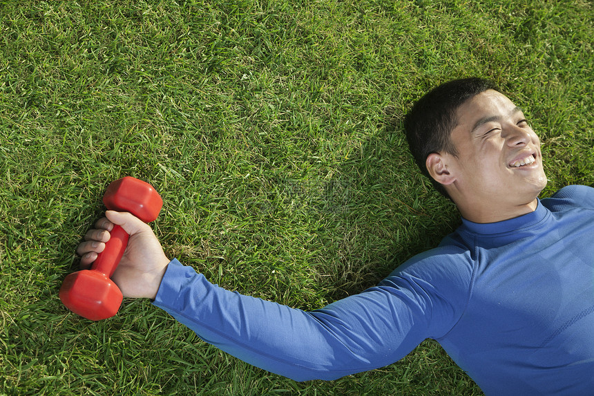 年轻的运动健壮的年轻人躺在草地上 和哑巴一起躺下 近距离接近图片