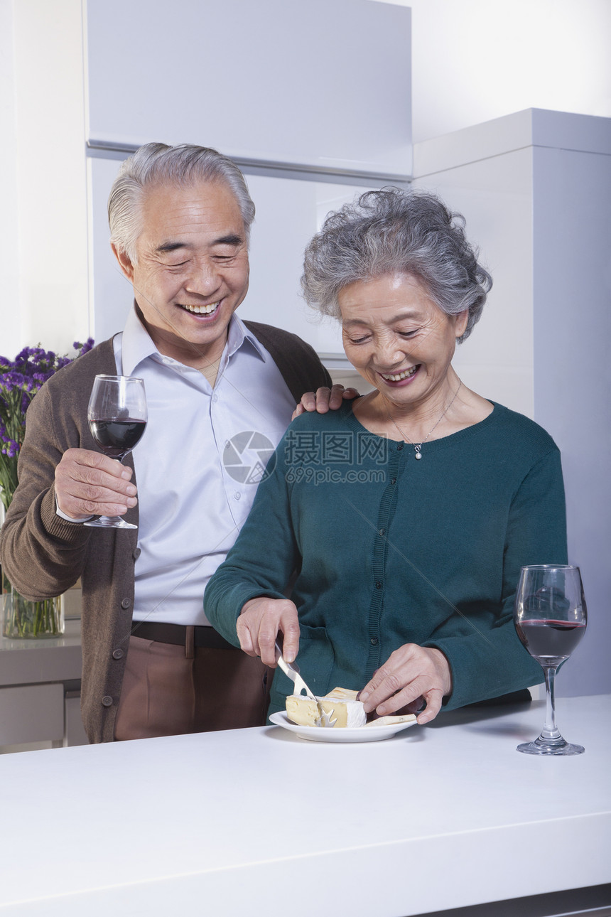 在厨房的老夫妇 饮酒和奶酪微笑享受收腰玻璃手臂菜刀幸福服装摄影团结图片