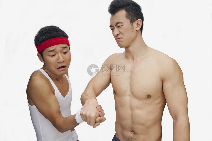 一名青年男子在摔臂摔跤和制片人拍摄时殴打另一名青年男子图片