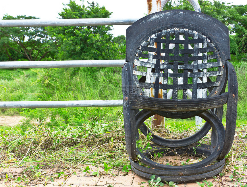 铁栅栏旁的旧椅子黑色装饰工作车轮座位雕刻木头个性家具小路图片