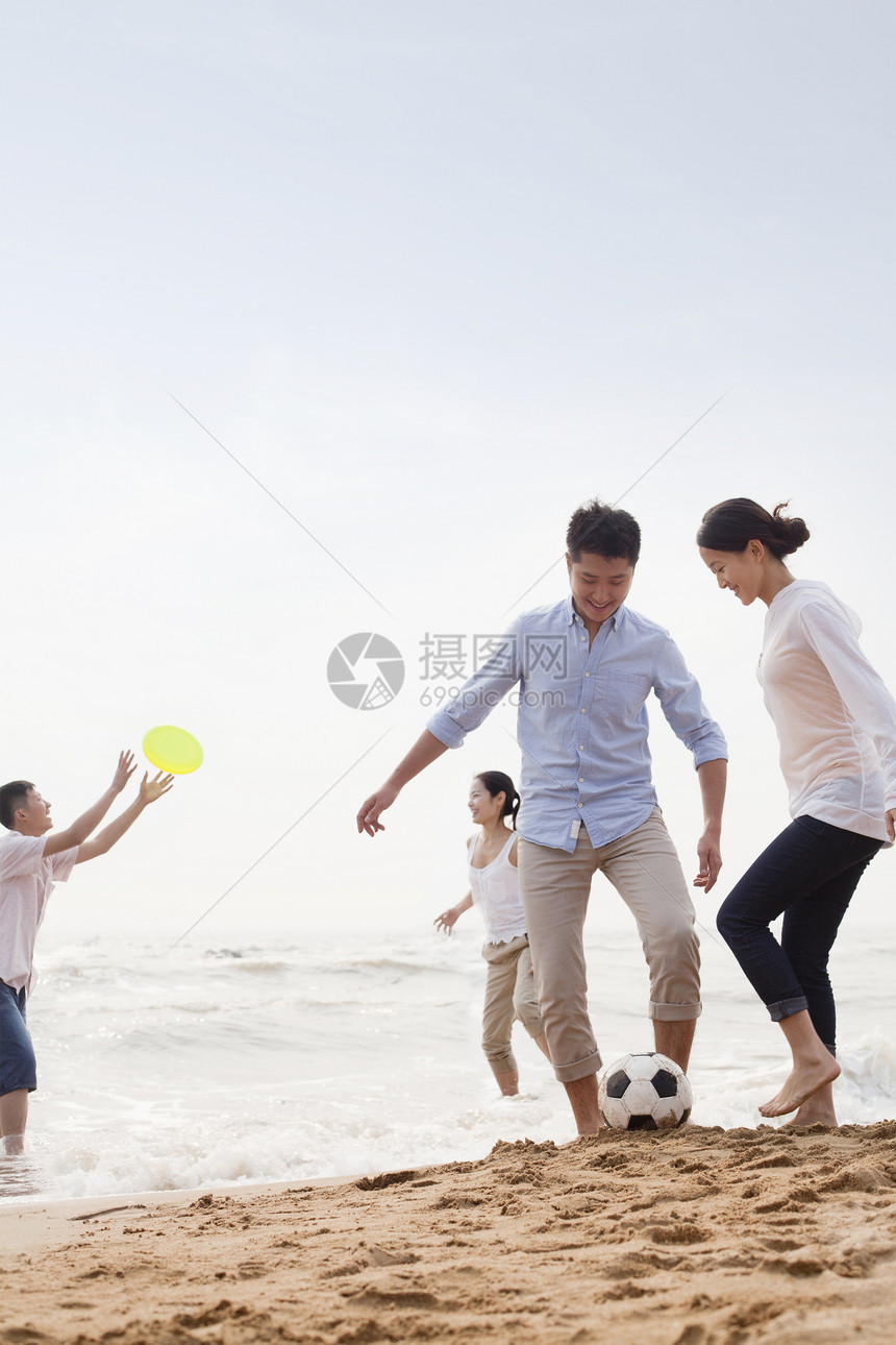 在中国海滩上玩足球和飞盘的四位年轻人图片