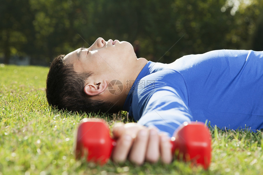 年轻的运动健壮的年轻人和哑巴躺在公园里图片