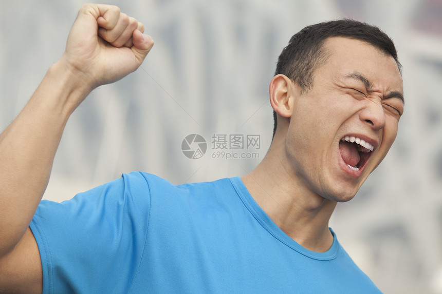 穿着蓝色T恤的年轻男子 举拳高举在空中 北京图片