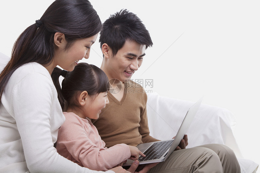 家人坐在沙发上看着笔记本电脑 摄影棚镜头活动父亲马尾辫黑发亲热女儿休闲团结年轻人女孩们图片