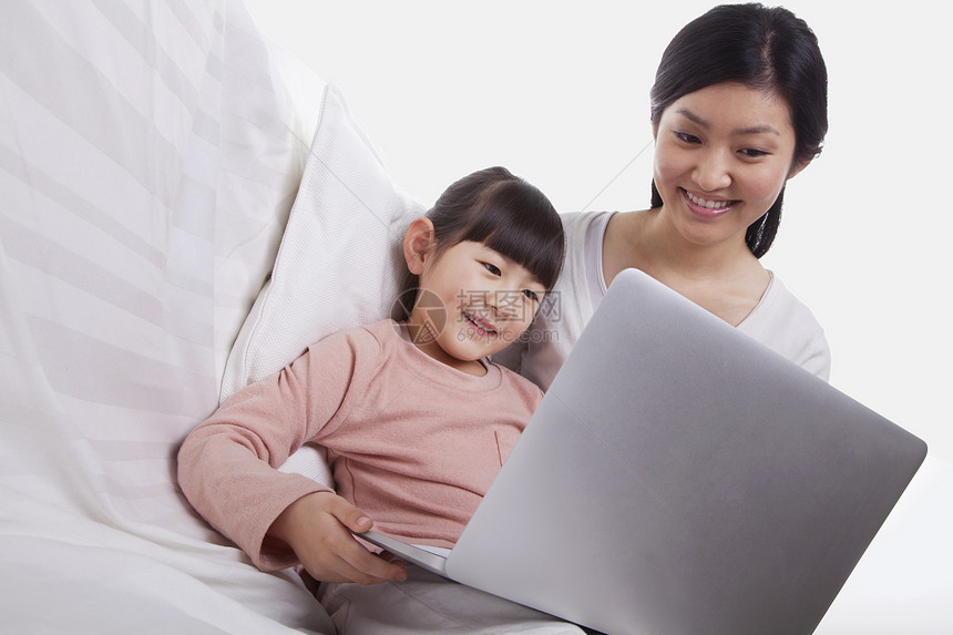 母亲和女儿坐在沙发上使用笔记本电脑倾斜孩子幸福黑发享受微笑女性亲热收腰活动童年图片