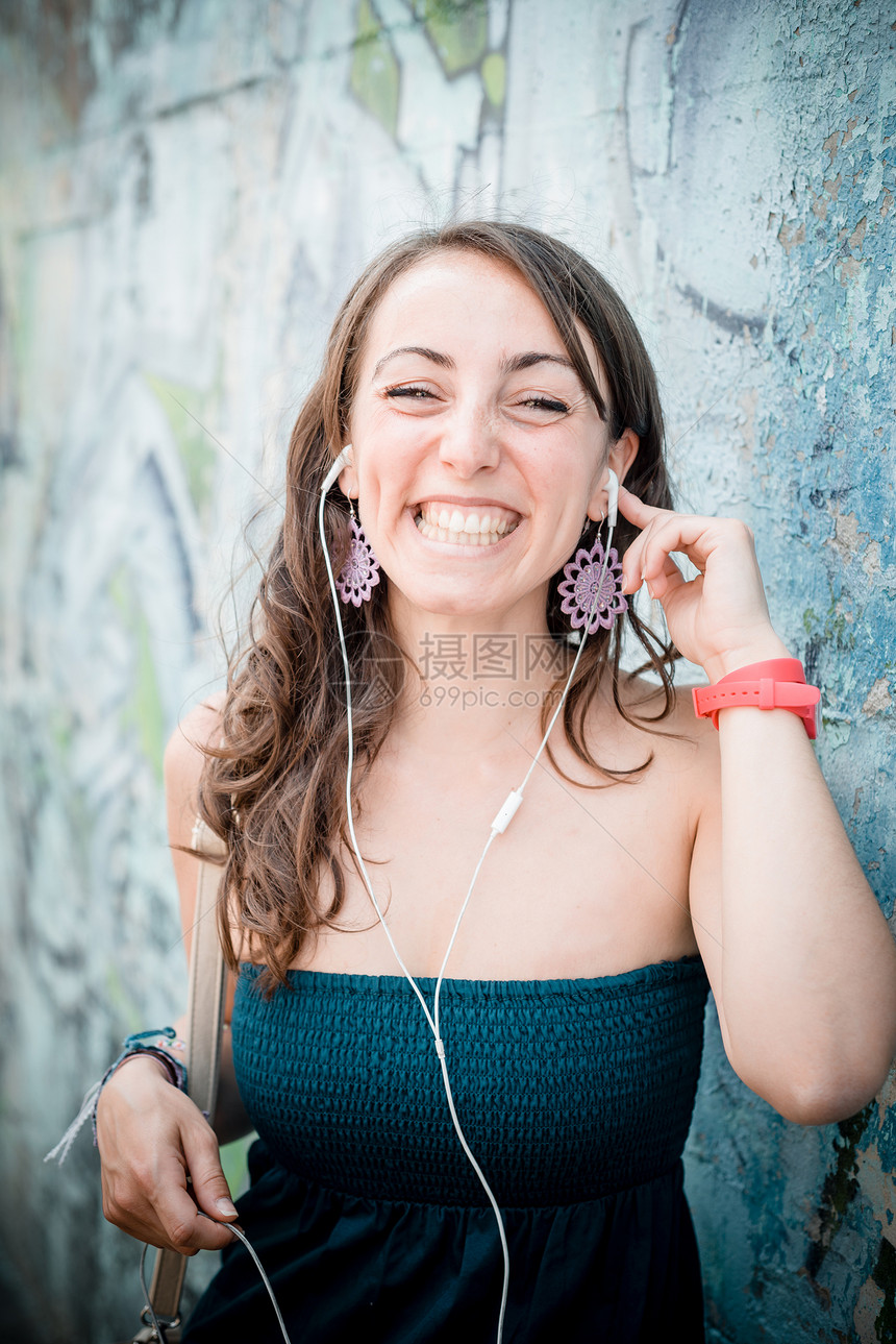 听音乐的美容女子女士音乐播放器音乐微笑放松城市耳机幸福街道图片