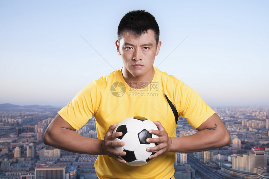 足球运动员将球放在胸前 城市背景图片