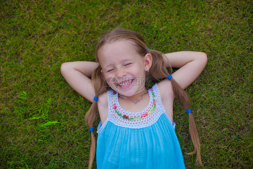 小女孩躺在房子附近的草地上 笑着笑着头发幸福阳光女孩孩子裙子花园季节微笑乐趣图片