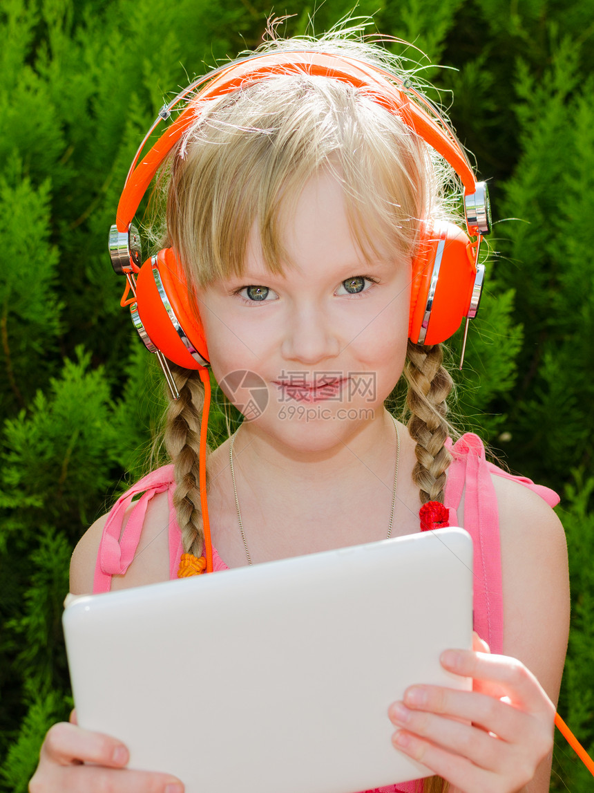 有平板电脑的可爱女孩 用耳机听音乐图片