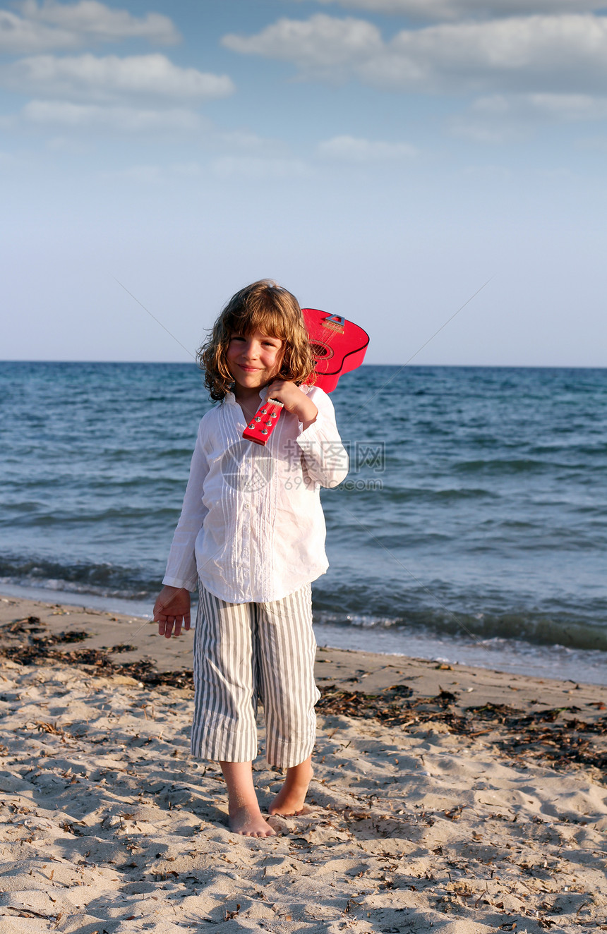 美丽的小女孩 在海滩上弹吉他图片