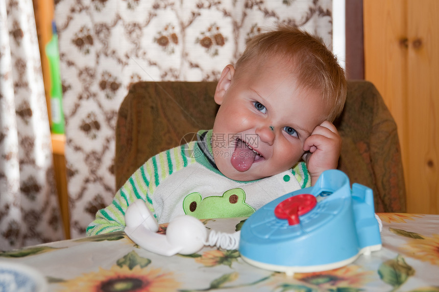 小男孩坐在桌子上孩子们男生划痕绿色鼻子婴儿电话儿童童年快乐图片