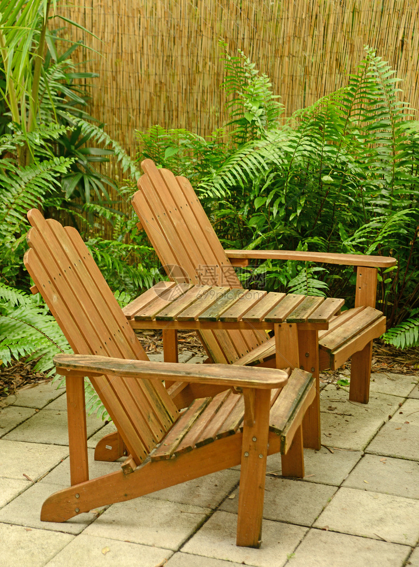 热带后院的木制Adirondack椅子图片