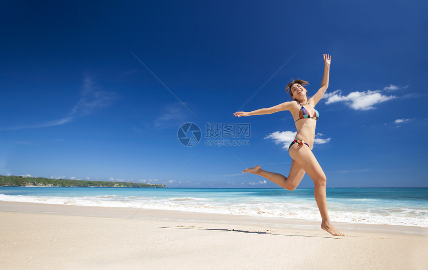 女人在海滩上跳跃天空成功游泳衣蓝色女孩海洋比基尼闲暇喜悦幸福图片