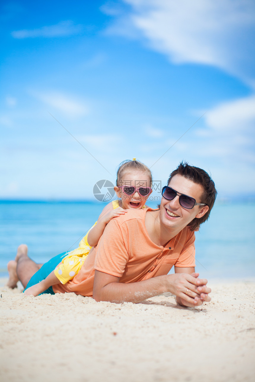 快乐的父亲和他可爱的小女儿 躺在白沙滩上图片