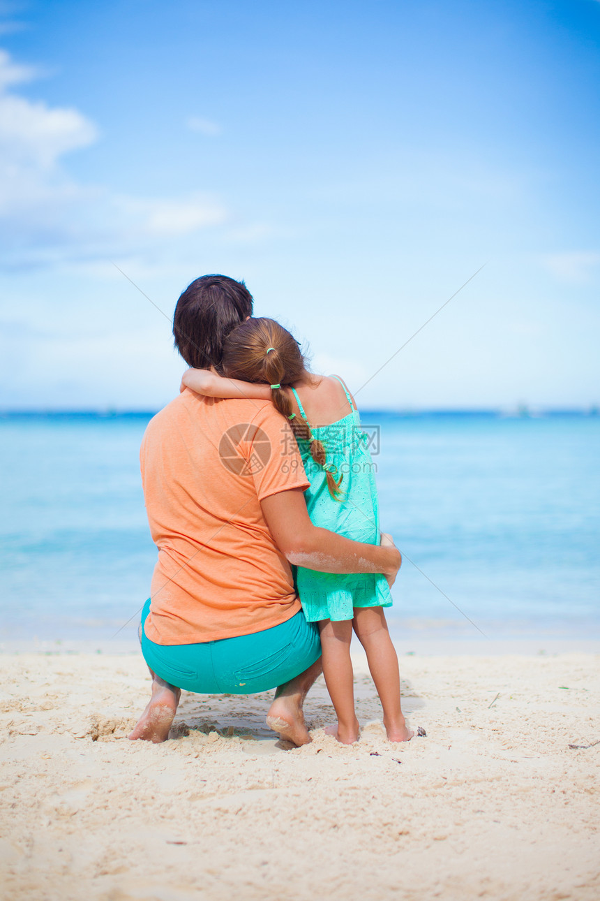 年轻父亲和可爱女儿的后视景 在沙滩上玩得开心图片