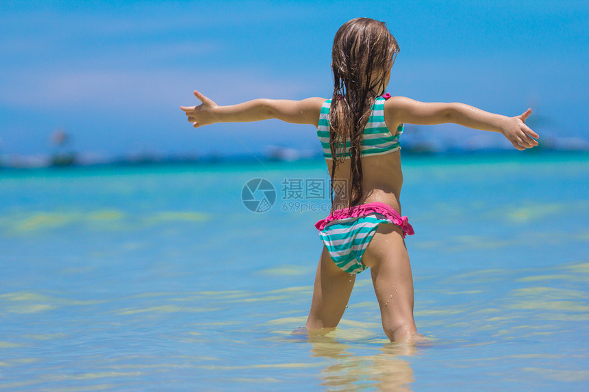 美丽的小女孩张开双臂 站在沙滩上女性海洋婴儿女儿泳装幸福童年海岸海滩海滨图片