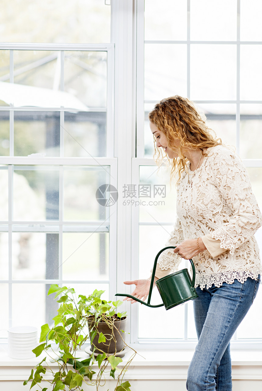 在家打水的微笑妇女窗户房子成人盆栽中年植物晴天女性日光金发图片