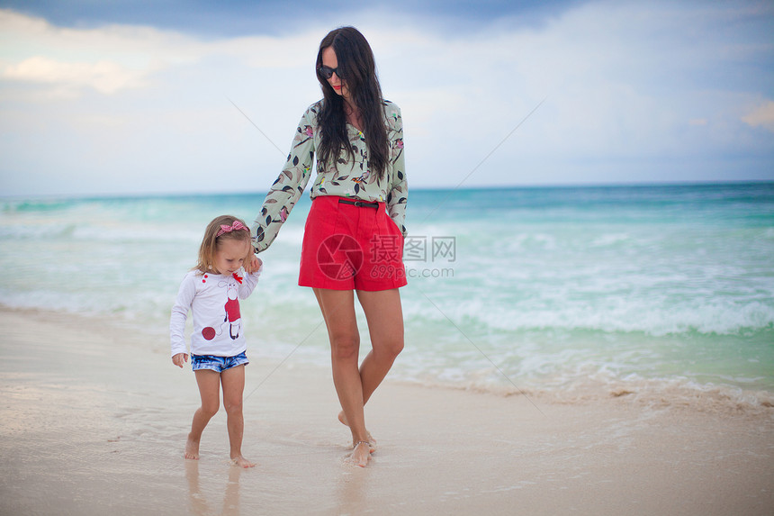 年轻美丽的母亲和可爱的小女儿在热带海滩上走动 散步于热带海滩图片