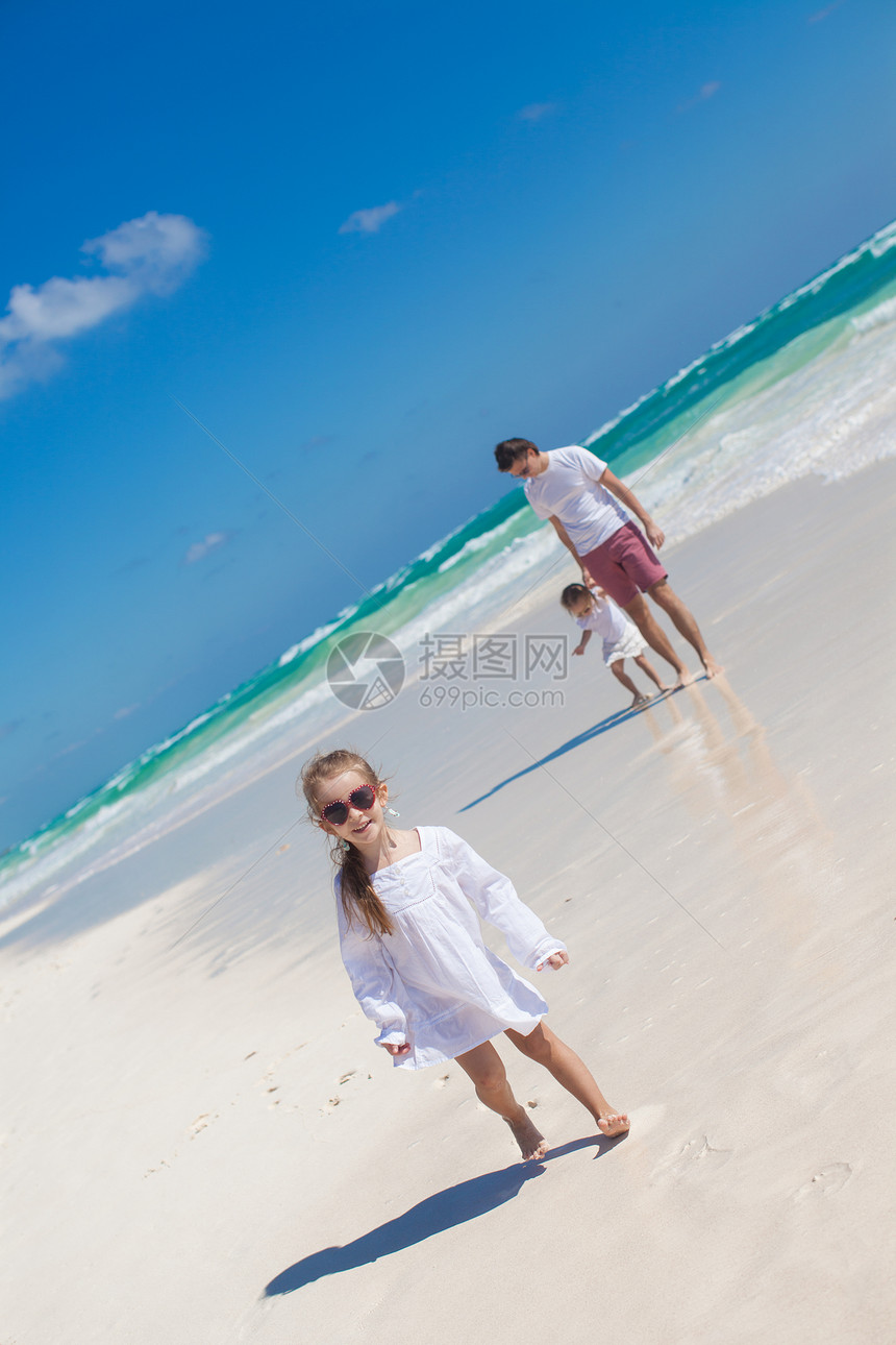 前景中有趣的大女儿和爸爸带着小女儿在沙滩上喜悦女孩婴儿享受海洋幸福男人海岸线海滩假期图片