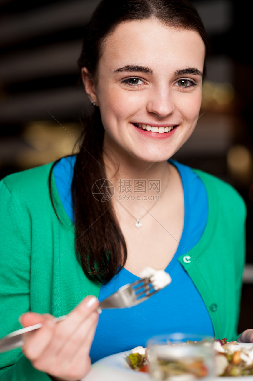 快乐的年轻女孩享受她的晚餐青少年微笑美食食物盘子女士女性餐厅桌子图片