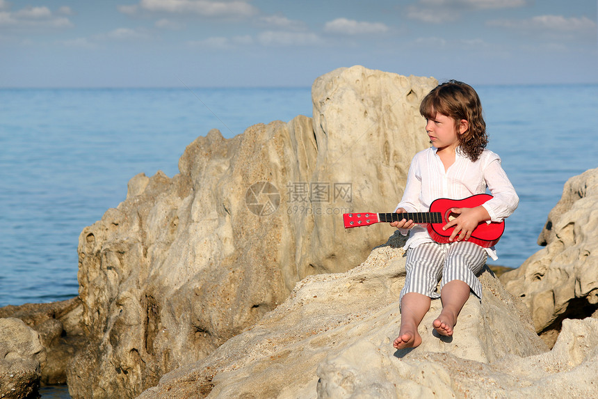 带着吉他坐在岩石上的小女孩图片