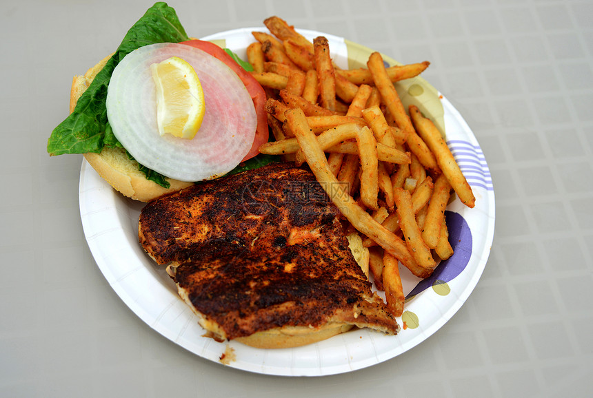 黑色的鱼三明治和盘子上的薯条图片