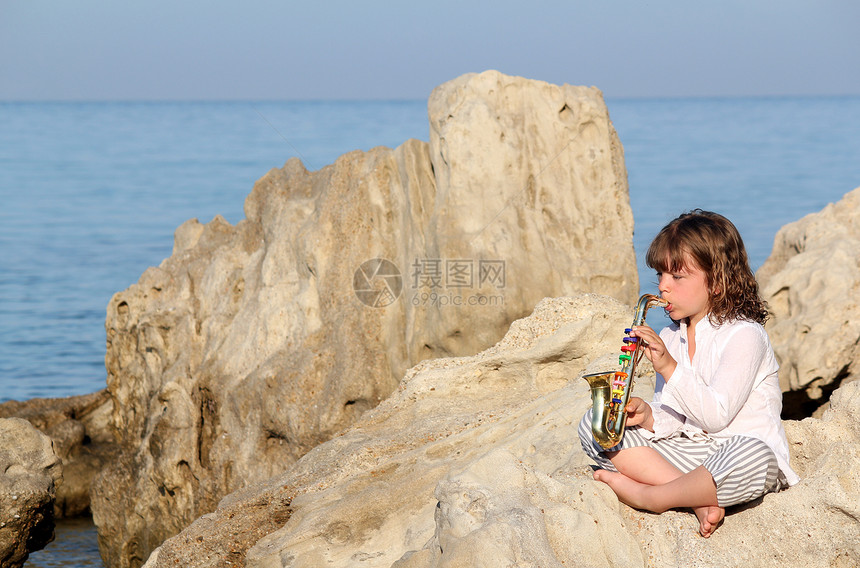 小女孩在海边玩萨克斯图片