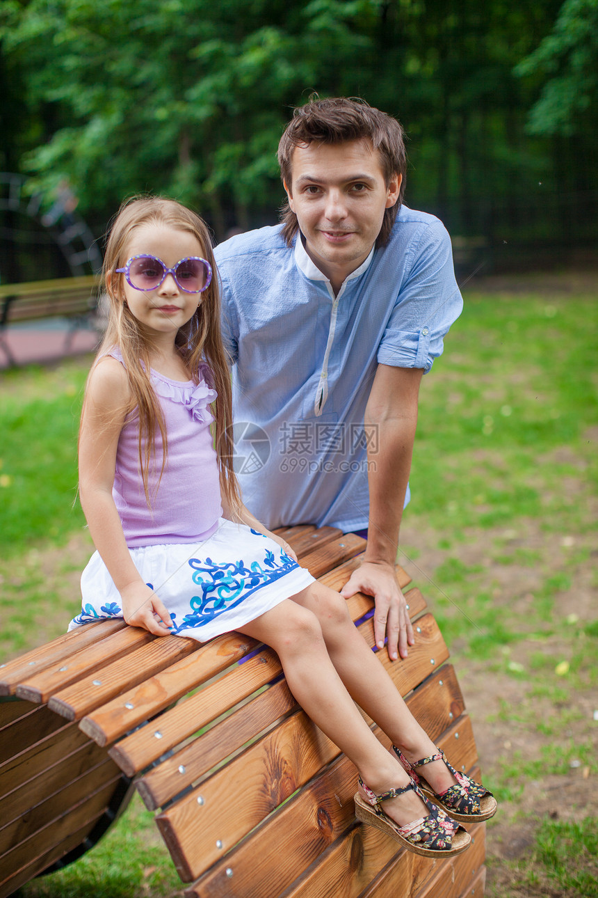 父亲和女儿坐在公园木板床上的画像图片