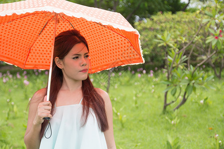 女人的伞年轻妇女和橙色雨伞假期人脸幸福公园微笑露齿橙子成人女性背景