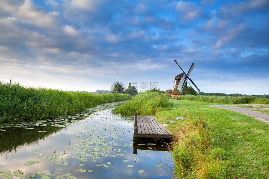 荷兰风车 沿河流行驶 有反光蓝天空图片
