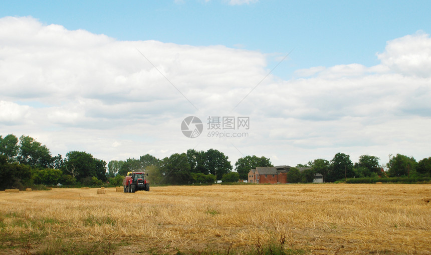 红拖拉机在农场田里采灌稻草图片