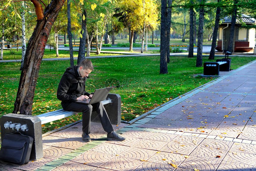 公园里有笔记本电脑的人工作互联网胡同叶子工具面漆男性头发操作成人图片