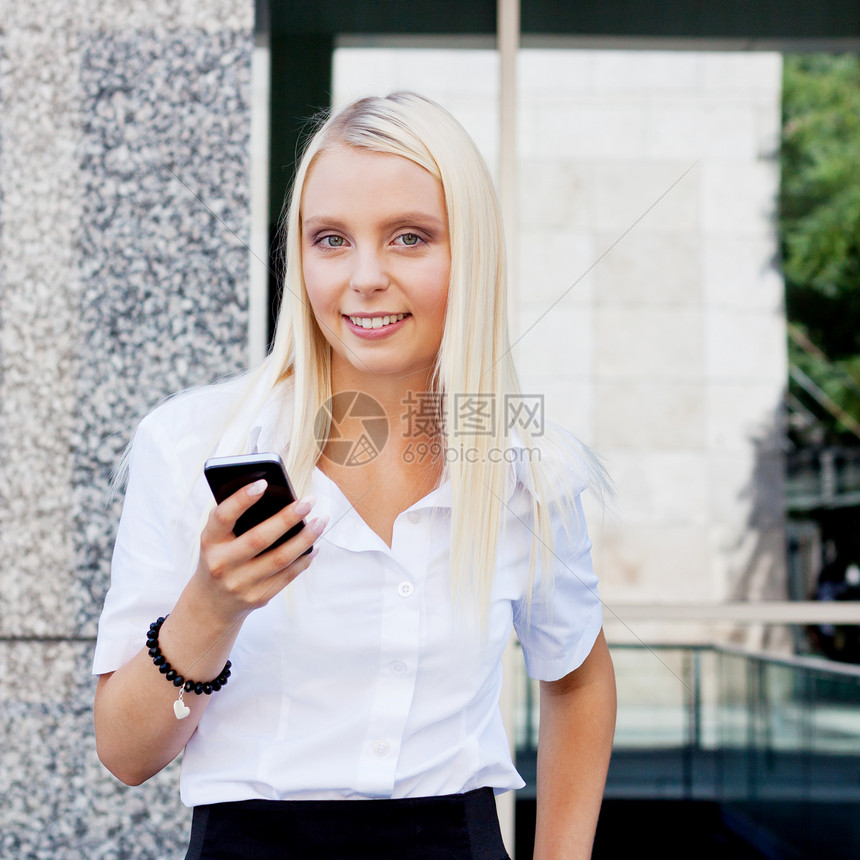 拥有智能手机的 笑着迷人的金发女商务人士头发触摸屏人士金发女郎女孩互联网屏幕办公室电话工作图片