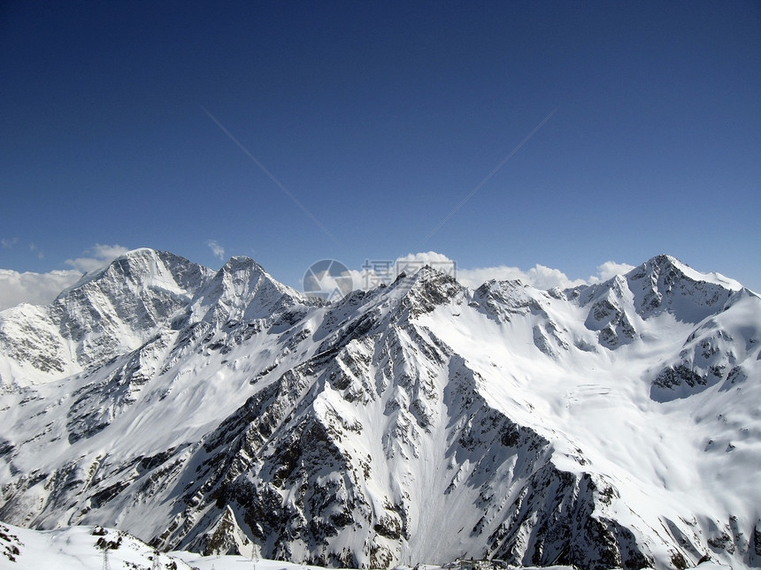 蓝天和云下高山危险滑雪天蓝色白色蓝色石头岩石天空季节滑冰图片