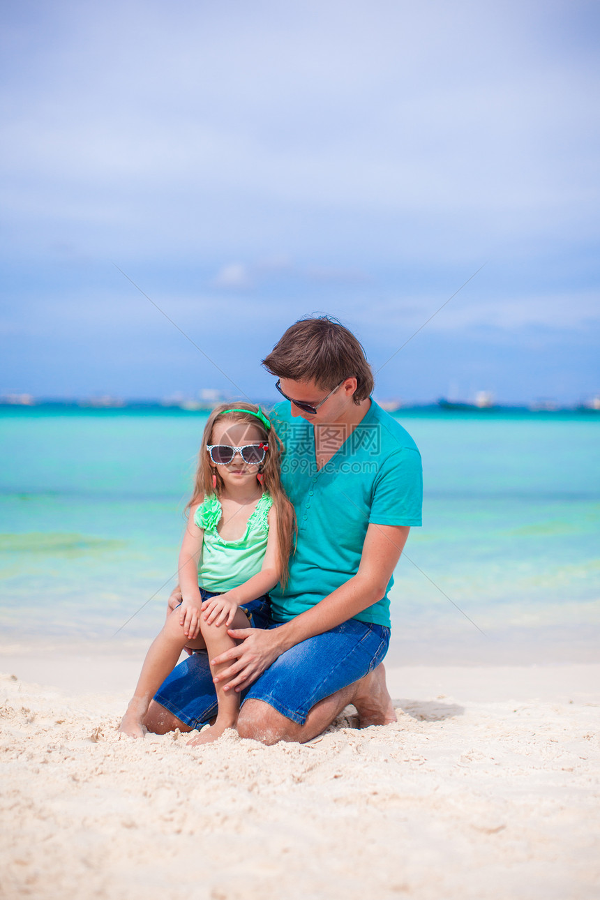 年轻父亲和他的小女儿坐在热带白色沙滩上幸福爸爸海洋男性海岸海岸线海滨情调异国父母图片