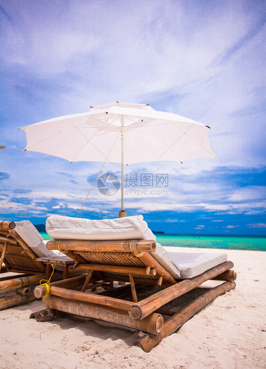 拥有雨伞和沙椅的热带空沙滩平地天堂景色椅子海景休息室情调晴天天蓝色蓝色海滩旅行异国图片
