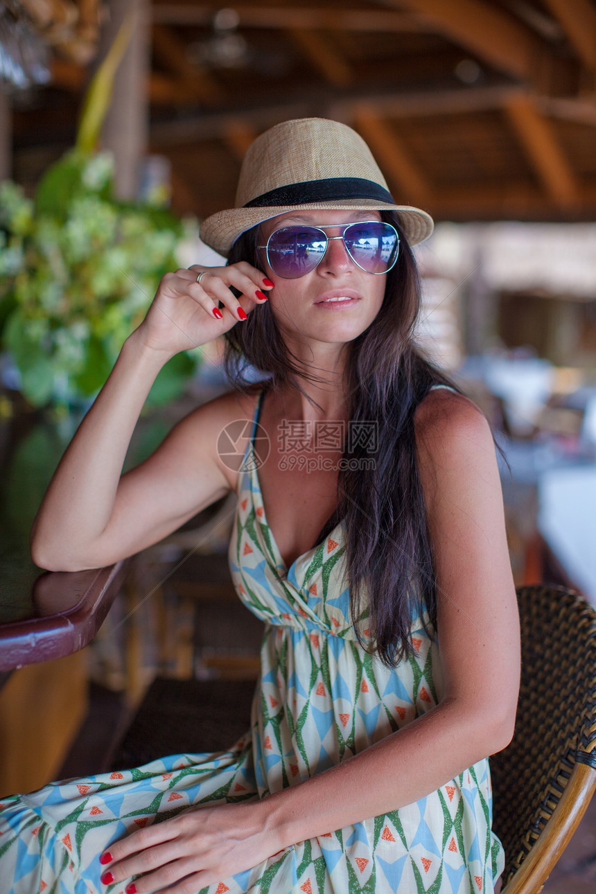 穿着长裙的美丽的黑发美女 在异国度假村酒吧附近放松场景棕褐色棕榈天堂天空女孩海滩旅行餐厅帽子图片