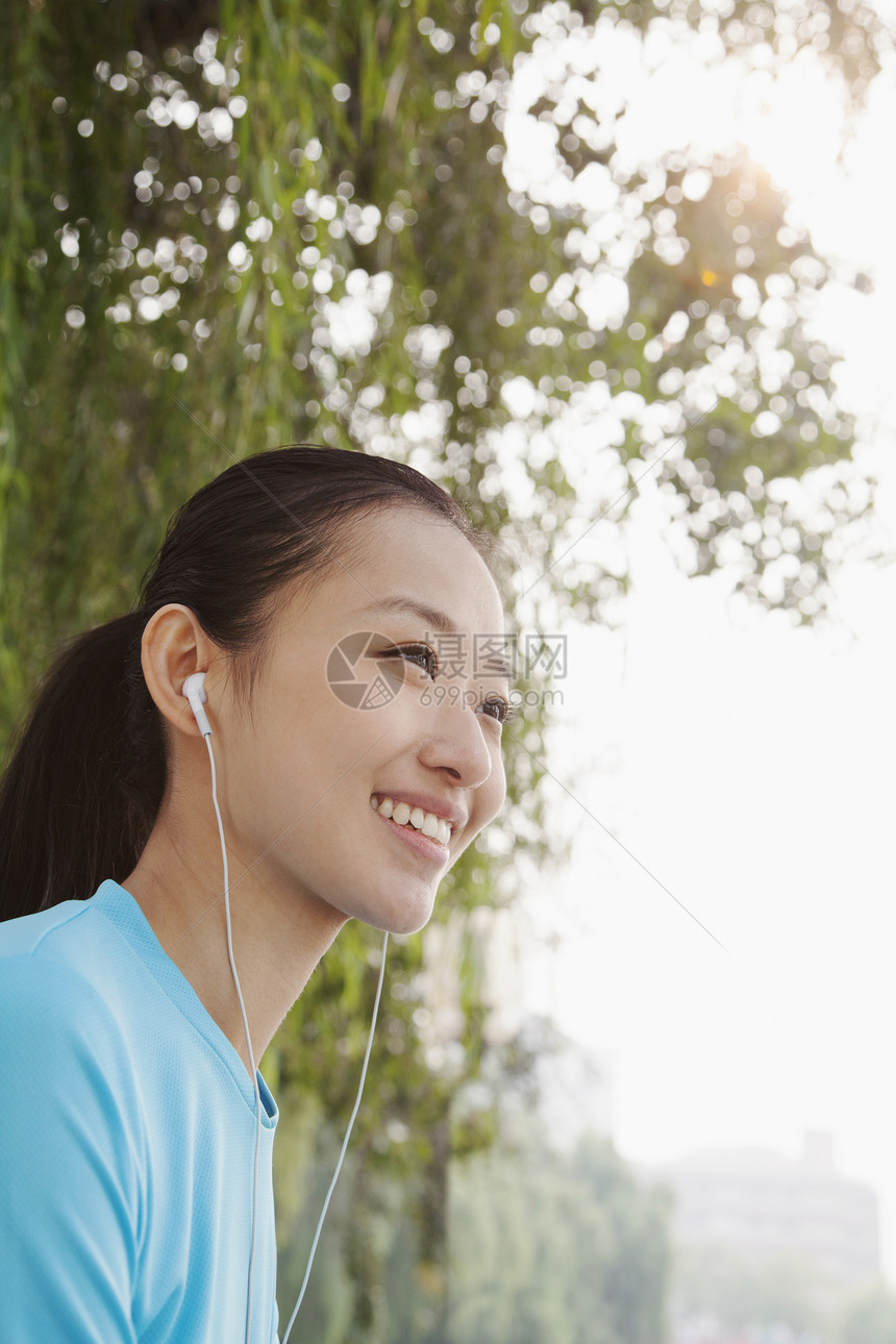 青年妇女聆听音乐会音乐省会享受听力活力低角度公园情绪服装倾斜图片