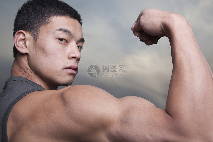 年轻人炫耀他的双臂肌肉人体手臂部位黑发摄影数字人类短发二头肌复合图片
