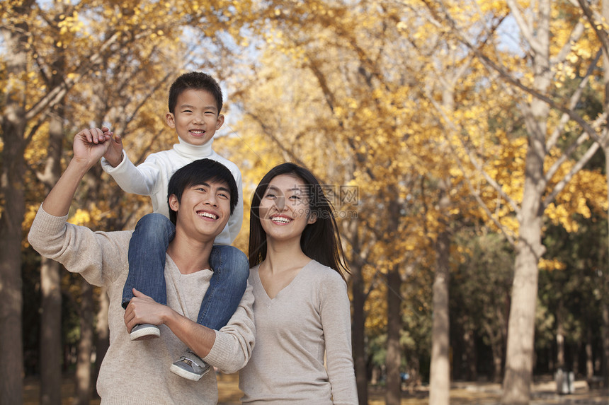 男孩坐在父亲肩上 在秋天的公园里和家人一起坐着长发微笑保暖女性情绪叶子黑发省会家庭孩子图片