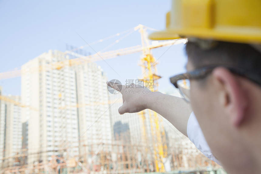 建筑师在建筑工地上指着摩天大楼图片