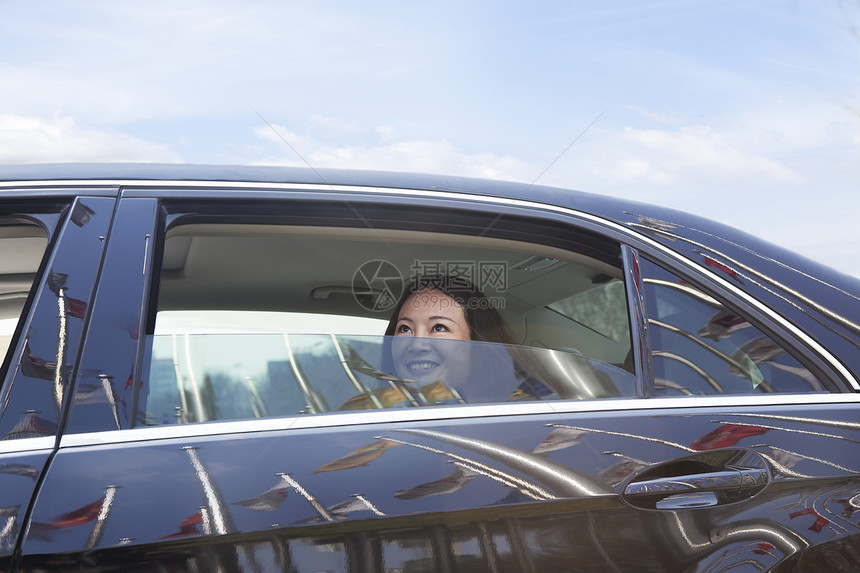 坐在车后座的年轻女子向窗外望去旗帜露齿窗户摄影水平车辆幸福旅行享受自由图片