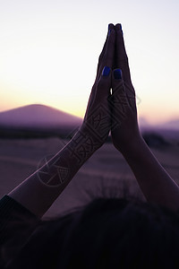 双手举过头顶在中国的沙漠中 双手合十祈祷的宁静年轻女子举过头顶 特写背景