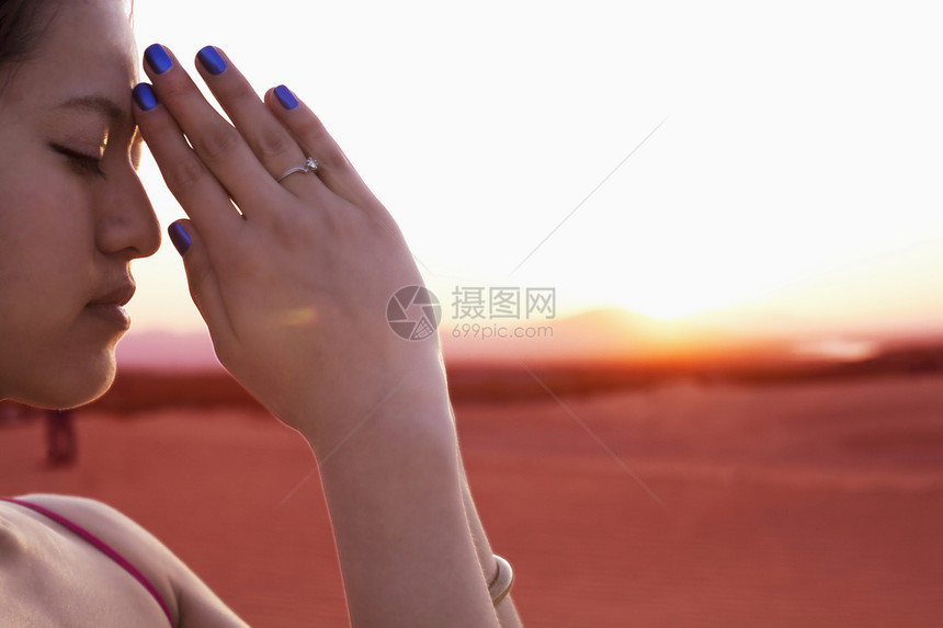 在中国沙漠中 双眼闭着 双手一起祷告的贞洁年轻女子 露出身姿势 从侧面看图片