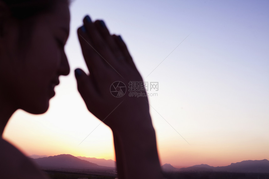 在中国的沙漠中 闭着眼睛双手合十祈祷的宁静年轻女性专注于背景图片