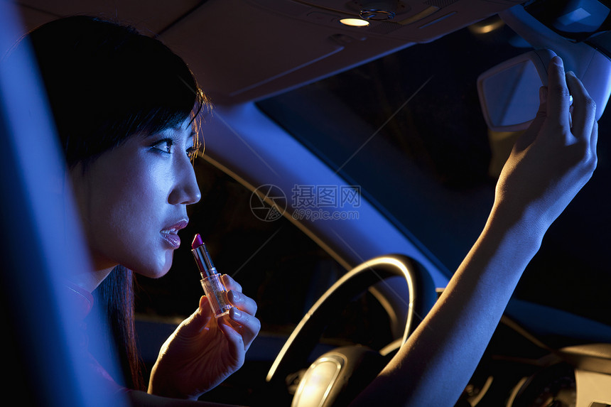 穿着中国传统服装的年轻美女 在夜里在车后视镜中涂口红 看车后面镜子图片