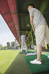年轻人在高尔夫球场挥棒打高尔夫球背景图片