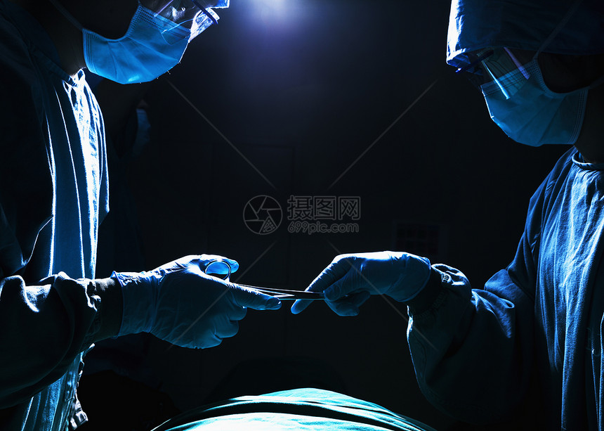 两名外科医生在黑暗的手术室工作并通过手术设备 该手术室收腰医护人员防护专注手术台面具保健医院权威手术帽图片
