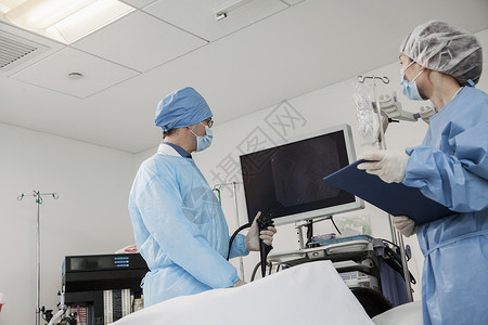 手术器材两名外科医生准备手术 病人躺下防护手术室保健手术衣医疗眼镜低角度检查倾斜年轻人背景
