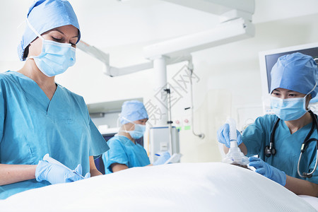 手术器材外科医生小组与一名躺在手术台上的病人一起工作背景